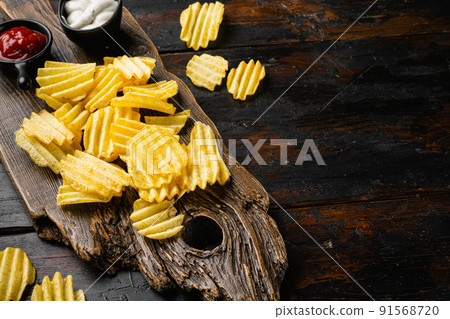 Wavy Lightly Salted Potato Chips on old dark wooden table background, with copy space for text Wavy Lightly Salted Potato Chips on old dark wooden table background, with copy space for text 91568720