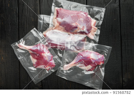 Fresh uncooked duck meat, legs and breast vacuum sealed, on black wooden table background, top view flat lay Fresh uncooked duck meat, legs and breast vacuum sealed, on black wooden table background, top view flat lay 91568782