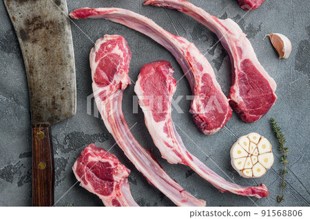 Raw fresh lamb loin chops, with ingredients carrot orange, herbs, and old butcher cleaver knife, on gray stone background, top view flat lay Raw fresh lamb loin chops, with ingredients carrot orange, herbs, and old butcher cleaver knife, on gray stone background, top view flat lay 91568806