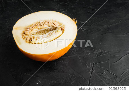 Ripe fresh yellow melon half, on black dark stone table background, with copy space for text Ripe fresh yellow melon half, on black dark stone table background, with copy space for text 91568925
