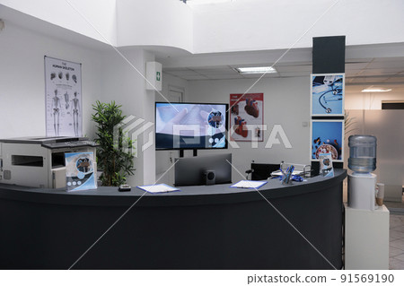 Nobody in hospital waiting room front desk with office supplies and promotional flyers in healthcare facility. Empty reception counter with no people at private practice clinic. 91569190