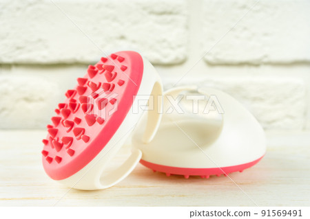 Hand massager with silicone spikes for anti-cellulite massage on white brick background. Hand massager with silicone spikes for anti-cellulite massage on white brick background. 91569491