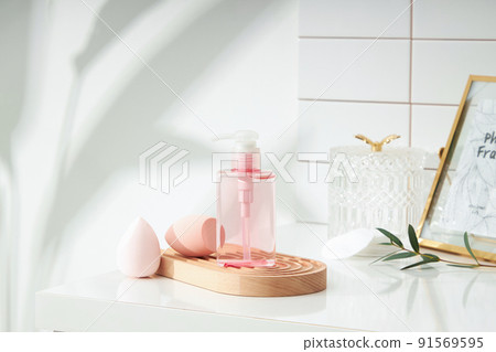 Cosmetics product and cotton towels, cottons pad with green plant on white table inside a bathroom background ceramic. Cosmetics product and cotton towels, cottons pad with green plant on white table inside a bathroom background ceramic. 91569595