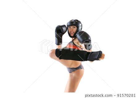 Enegry. Young female kickboxer wearing sports uniform and protective equipment in action isolated on white background. Sport, competition, power concept. Enegry. Young female kickboxer wearing sports uniform and protective equipment in action isolated on white background. Sport, competition, power concept. 91570281