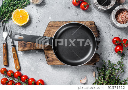 Various organic spices, herbs and ingredients around empty aged cooking skillet. Gray background. Top view. Copy space Various organic spices, herbs and ingredients around empty aged cooking skillet. Gray background. Top view. Copy space 91571312