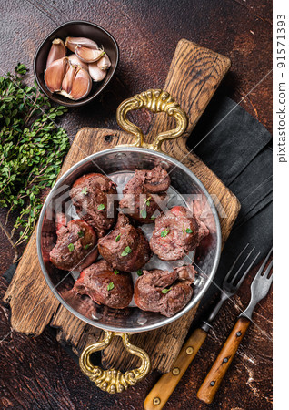 Roasted beef kidney, offal meat in skillet with herbs. Dark background. Top view Roasted beef kidney, offal meat in skillet with herbs. Dark background. Top view 91571393