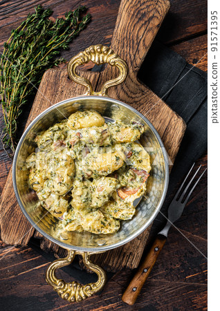 Italian Gnocchi potato pasta with spinach and parmesan in skillet. Wooden background. Top view 91571395