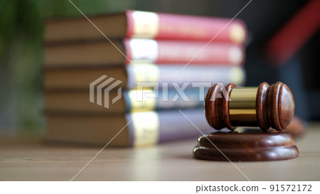 Wooden judge gavel with golden strip on sounding block 91572172