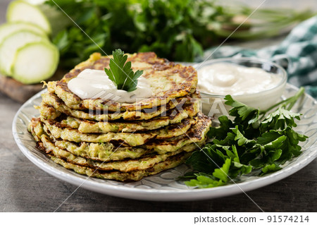 Zucchini fritters with yogurt sauce on wooden table 91574214