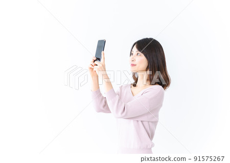 A young woman taking a smartphone shot with a smile A young woman taking a smartphone shot with a smile 91575267