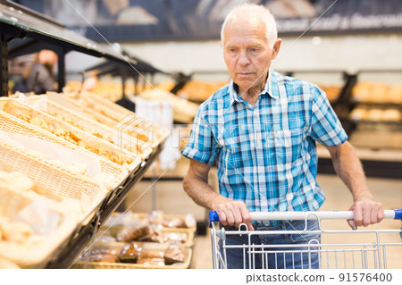 mature senor choosing bread and baking in grocery section of supermarket mature senor choosing bread and baking in grocery section of supermarket 91576400