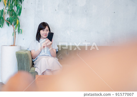 Business woman using a smartphone in the lounge 91577007