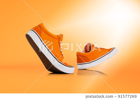 Modern unisex footwear, sneakers isolated on orange background. Fashionable stylish sports casual shoes. Creative minimalistic layout with footwear. Modern unisex footwear, sneakers isolated on orange background. Fashionable stylish sports casual shoes. Creative minimalistic layout with footwear. 91577269
