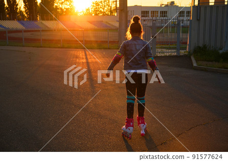 Girl riding roller skates in the park 91577624