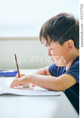 Elementary school boy writing in a notebook 91577702