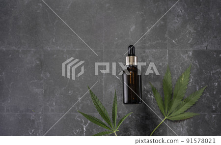 glass bottle with CBD oil, THC tincture and hemp leaves on a marble background. Flat lay, minimalism. Cosmetics CBD. 91578021