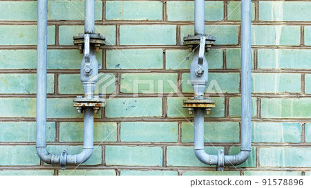 Pipeline with gas supply outlets on a green brick wall 91578896