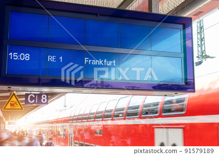 Close-up sign data information timetable digital display board against fast moving modern regional red double decker express train at sunset on german railway platform. Railroad travel ticket concept 91579189