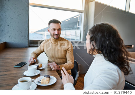 Charming couple in love snacking together in the international airport cafeteria, awaiting customs and passenger control before boarding the flight 91579440