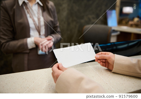 Close-up of woman hands holding ticket with copy space for advertising text while standing by check-in counter in the airport departure terminal Close-up of woman hands holding ticket with copy space for advertising text while standing by check-in counter in the airport departure terminal 91579600