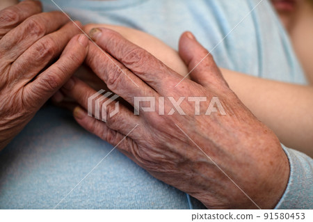 The wrinkled hands of an old grandmother hold the hands of a grandson who hugs her. The concept of love and care. Slow life The wrinkled hands of an old grandmother hold the hands of a grandson who hugs her. The concept of love and care. Slow life 91580453