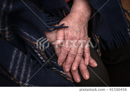 The hands of a mature 93-year-old grandmother with wrinkles lie on a cozy blanket at home. The concept of love and care. Slow movement 91580456