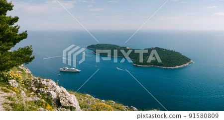 Lokrum is a small island in the Adriatic Sea, near Dubrovnik, Croatia. A small cruise ship moored near the island. View from the observation deck from the mountain above Dubrovnik. 91580809