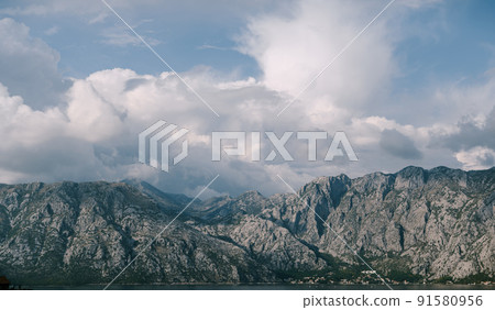 White cumulus clouds over the Kotor Bay mountain range 91580956