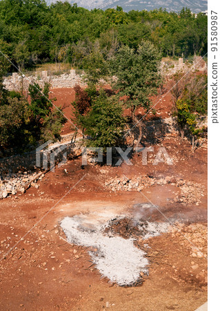 Top view of a red quarry with stones surrounded by greenery 91580987