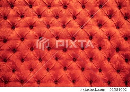 Close up background texture of scarlet red capitone genuine leather, retro Chesterfield style soft tufted furniture upholstery with deep diamond pattern and buttons Close up background texture of scarlet red capitone genuine leather, retro Chesterfield style soft tufted furniture upholstery with deep diamond pattern and buttons 91581002