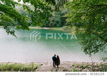 Man and woman stand on the shore of a lake in the Biogradska Gora park. Back view 91581135