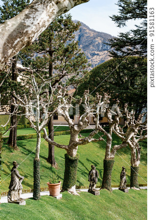 Stone sculptures among plane trees in the park of Villa Balbianello. Lake Como, Italy Stone sculptures among plane trees in the park of Villa Balbianello. Lake Como, Italy 91581163