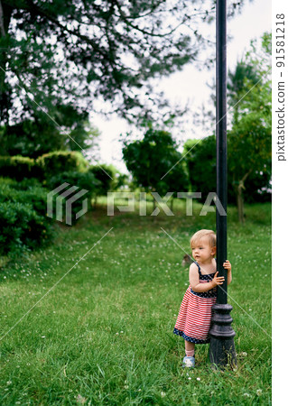 Little girl holding hands for a lantern in a green park 91581218