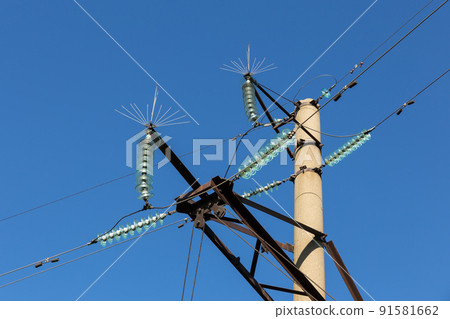 Concrete electricity pylon with glass insulators and bird spikes. Electric power concept. Bird protection for power lines. 91581662