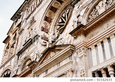 Statues, carved molds, columns and rose window on the facade of the Colleoni Chapel. Bergamo, Italy Statues, carved molds, columns and rose window on the facade of the Colleoni Chapel. Bergamo, Italy 91582635