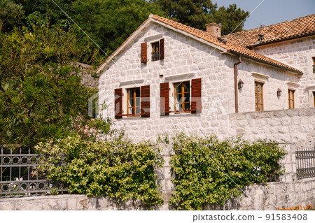 White stone building facade with brown wooden shutters on the windows White stone building facade with brown wooden shutters on the windows 91583408