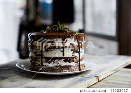 Chocolate brownie cake topped with dark chocolate ganache on a wooden table Chocolate brownie cake topped with dark chocolate ganache on a wooden table 91583487