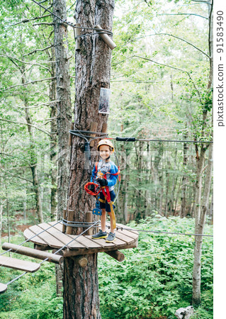 Boy in protective gear stands on a wooden platform in front of the agility bridge Boy in protective gear stands on a wooden platform in front of the agility bridge 91583490