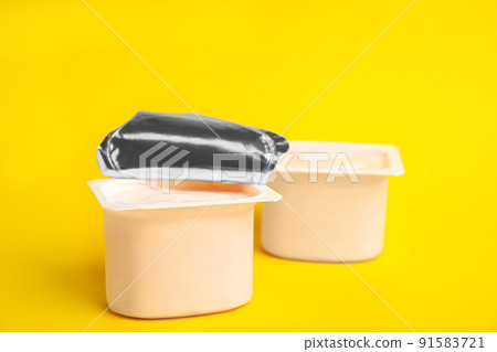 Tasty organic yogurt in plastic cups on yellow background 91583721