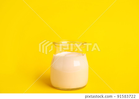 Tasty organic yogurt in glass jar on yellow background 91583722