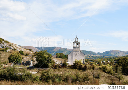 Old chapel with a bell tower near the cemetery in the field against the background of mountains Old chapel with a bell tower near the cemetery in the field against the background of mountains 91583786