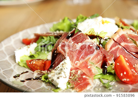 Delicious prosciutto salad with vegetables on plate, closeup 91583896