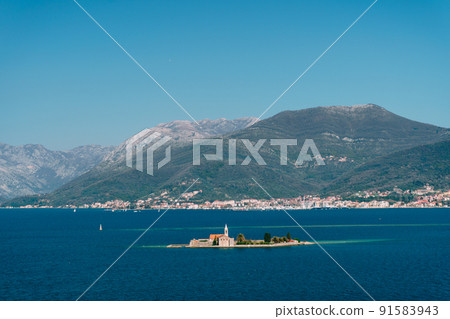 Island of Otocic Gospa in the bay against the backdrop of the town on the coast. Montenegro 91583943