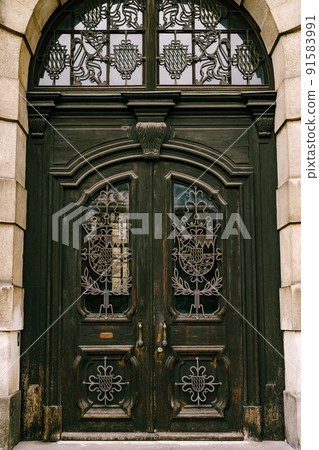 Antique wooden door in a stone building with glass inserts and metal forging Antique wooden door in a stone building with glass inserts and metal forging 91583991