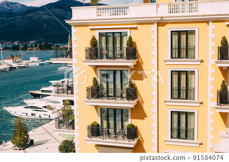 Facade of a modern building with balconies on the background of the pier with yachts in the resort of Porto Facade of a modern building with balconies on the background of the pier with yachts in the resort of Porto 91584074