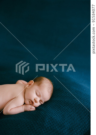 Portrait of a baby sleeping on a blue blanket on a tummy Portrait of a baby sleeping on a blue blanket on a tummy 91584077