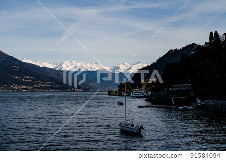 Sailing yacht sails on Lake Como past the coast of Varenna. Italy 91584094