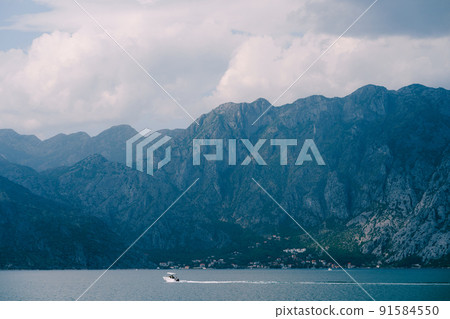 Motor boat sails along the Kotor Bay against the backdrop of mountains Motor boat sails along the Kotor Bay against the backdrop of mountains 91584550