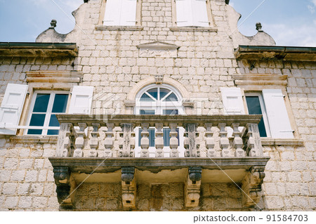 House facade with shutters on the windows, an attic and a stone balcony 91584703