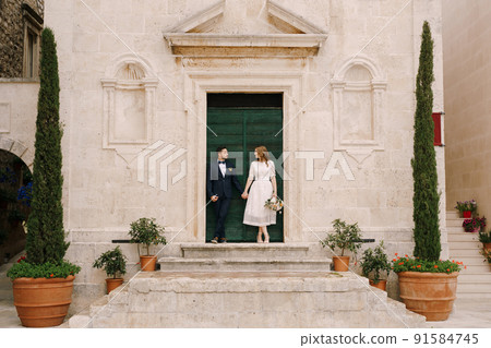 Bride and groom stand on the porch of the Church of St. Mark the Apostle. Montenegro 91584745